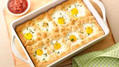 an egg and cheese casserole in a white dish on a wooden cutting board