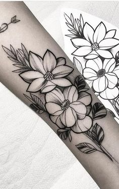 a black and white flower tattoo on the left arm, with flowers in the background