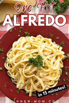 a red plate topped with pasta and parsley on top of a checkered table cloth