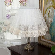 a lamp that is sitting on top of a table next to a painting and flowers