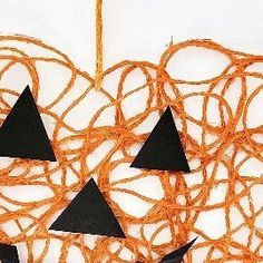 an orange string with black triangles hanging from it's sides on a white wall