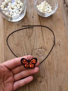 a hand holding a butterfly on top of a wooden table next to two bowls filled with food