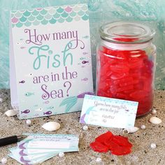 a jar filled with red gummy bears next to a sign that says how many fish are in the sea?