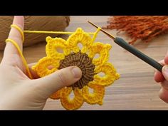 someone is crocheting a yellow flower on a piece of yarn with a needle