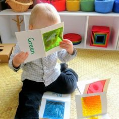 a toddler sitting on the floor reading a book in front of colorful blocks and toys