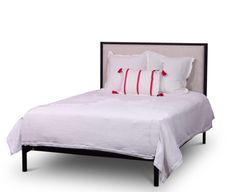 a bed with white sheets and red pillows on it's headboard, in front of a white background