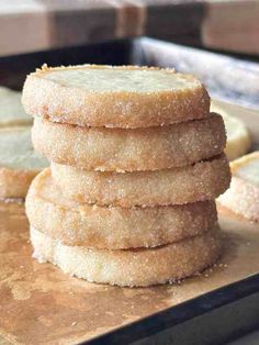 a stack of sugar cookies sitting on top of a wooden cutting board