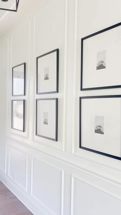 white wall with black framed pictures on it