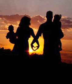 a family silhouetted against the setting sun with their hands in the shape of a heart