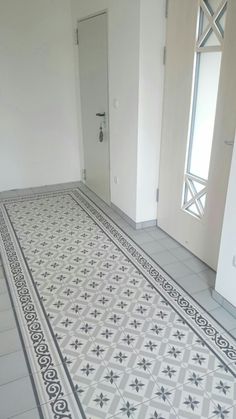 an empty room with white walls and black and white floor tiles on the floor, in front of a door