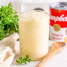 a jar filled with dressing next to a wooden spoon and some parsley on the table