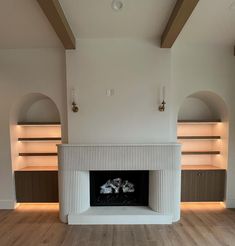 an empty living room with a fireplace and built in shelves