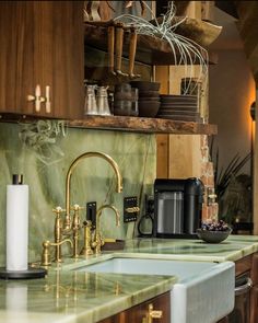 a kitchen with green marble counter tops and gold faucets on the sink area