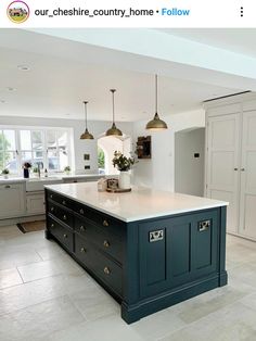 a large kitchen with an island in the middle and two pendant lights hanging from the ceiling