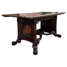 an ornate wooden table with carvings on the top and bottom, against a white background