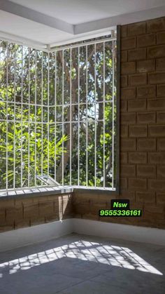 an empty room with large windows and bars on the wall, in front of trees