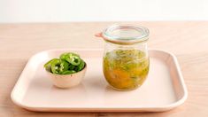 a glass jar filled with green liquid next to a small bowl