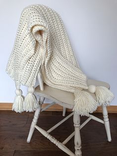 a white chair with a blanket draped over it's back and tasselled legs