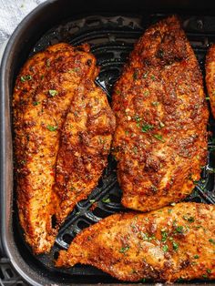 four pieces of chicken in a frying pan with parsley on the top and bottom