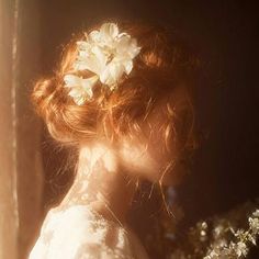 a woman with red hair wearing a white dress and flower in it's hair