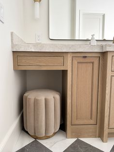 a bathroom vanity with a stool underneath it and a mirror on the wall behind it