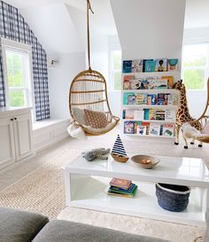 a living room with two hanging chairs and a white coffee table in front of a window