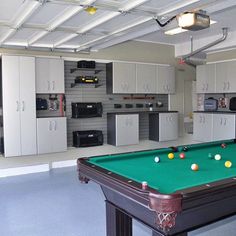 a pool table in the middle of a room with cabinets and appliances on either side