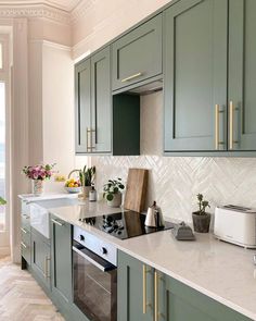 an image of a kitchen setting with green cabinets and marble counter tops on instagram