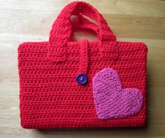 a crocheted red bag with a pink heart on the front and purple heart on the back