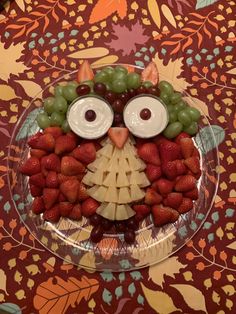 a plate topped with fruit and an owl face made out of grapes, strawberries