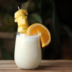 an orange slice sticking out of the top of a glass filled with milk and fruit