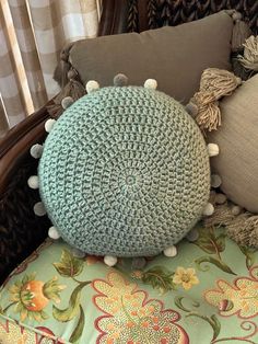 a green pillow sitting on top of a chair with pom poms around it