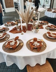 a white table topped with lots of plates and place settings covered in brown napkins