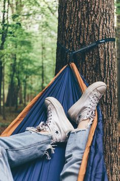 a person laying in a hammock with their feet propped up on the ground