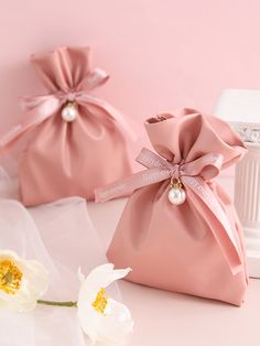 two pink bags with bows and pearls are sitting next to each other on a table