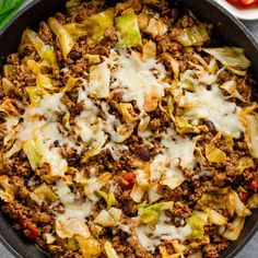 a skillet filled with ground beef and cabbage covered in melted cheese on top of a table