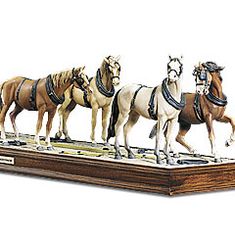 three horses are standing on a wooden base