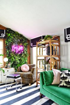 a living room filled with furniture and a green couch next to a plant covered wall