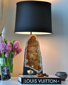 a table with a lamp and some flowers on it next to a book that says louis vuitton