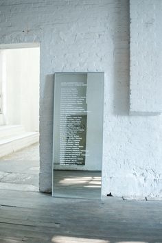 an empty room with white walls and wooden flooring has a large glass sign on the wall