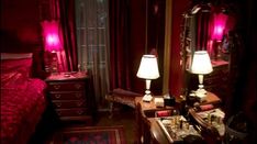 a bedroom with red walls and two lamps on the nightstands in front of it