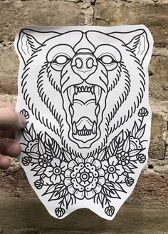 a hand holding up a sticker with an image of a bear's head