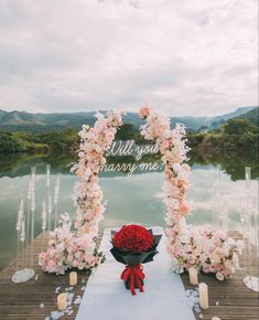 an outdoor ceremony setup with flowers and candles on the ground, along with a sign that says'all you marry me '