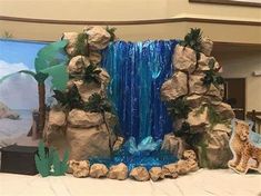 a fake waterfall is in the middle of a room with rocks and plants on it