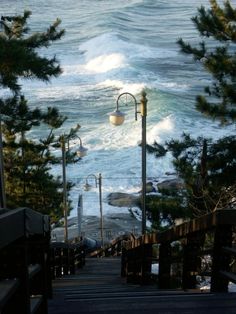 stairs lead down to the ocean with waves crashing on the shore behind them and street lights