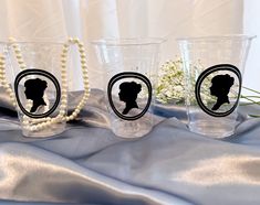 three shot glasses with the silhouettes of two women and a pearl beaded necklace