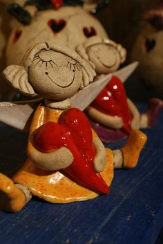 two ceramic figurines sitting next to each other on a blue table with hearts