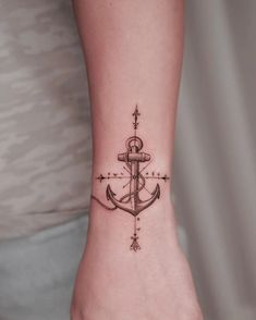 a small anchor tattoo on the wrist is shown in black and grey ink, with stars around it