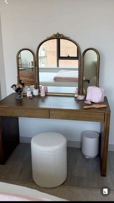 a vanity table with mirror and stool in a white room next to a large window