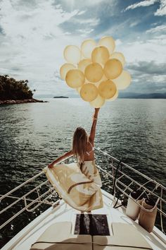 a woman on a boat holding balloons in the air